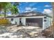 Exterior shot featuring a two-car garage and long driveway, surrounded by mature landscaping and a green lawn at 1484 Lake Francis Dr, Apopka, FL 32712