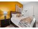 Comfortable bedroom features a decorative goldenrod wall, modern furnishings and accents, and plenty of natural light at 1526 Euston Dr, Reunion, FL 34747
