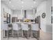 Well-lit kitchen with white cabinets, quartz countertops, a large island with seating and modern pendant lights at 1526 Euston Dr, Reunion, FL 34747