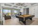 Bright living room with coffered ceiling, pool table, and scenic views from the private balcony at 1526 Euston Dr, Reunion, FL 34747