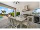An outdoor kitchen and dining area with a built-in grill, stainless steel vent, dining table and a view of the pool and yard at 1526 Euston Dr, Reunion, FL 34747