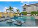 Refreshing pool with in-water lounge chairs, surrounded by palm trees and well-manicured landscaping at 1526 Euston Dr, Reunion, FL 34747