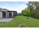 A well-maintained backyard features a screened porch, lush green grass, and mature trees at 17676 Passionflower Cir, Clermont, FL 34714
