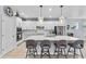 Spacious kitchen featuring white cabinets, a large island with seating, stainless appliances, and sleek pendant lights at 17676 Passionflower Cir, Clermont, FL 34714