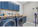 Well-equipped laundry room with blue cabinets, butcher block countertops, washer, and dryer at 17676 Passionflower Cir, Clermont, FL 34714