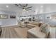 Spacious open-concept living room with a large sectional sofa, modern ceiling fan, and a view of the kitchen at 17676 Passionflower Cir, Clermont, FL 34714