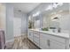 Elegant main bathroom featuring double sinks, modern lighting, and a walk-in shower with glass partition at 17676 Passionflower Cir, Clermont, FL 34714