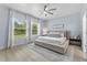 Bright bedroom with a large bed, neutral decor, ceiling fan, and two large windows with a lush view at 17676 Passionflower Cir, Clermont, FL 34714
