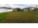 A full view of a large backyard with green grass, new trees, and white vinyl fencing at 1792 Bull Hill Rd, Kissimmee, FL 34744