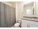 Well-lit bathroom features a shower with gray curtain and granite vanity at 1792 Bull Hill Rd, Kissimmee, FL 34744