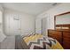 Bright bedroom with a dresser, closet, and a comfortable bed featuring a colorful chevron patterned comforter at 1792 Bull Hill Rd, Kissimmee, FL 34744