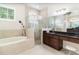 Luxurious bathroom featuring a glass walk-in shower, a soaking tub, and granite counters at 2588 Gabrielle Woods Pl, Oviedo, FL 32765