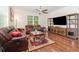 Comfortable living room with ceiling fan, wood floors, a brown leather sofa, and a large TV at 2588 Gabrielle Woods Pl, Oviedo, FL 32765