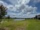 Expansive backyard with a scenic lake view, surrounded by well-maintained landscaping and beautiful blue skies at 3891 Sagefield Dr, Harmony, FL 34773