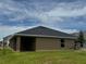 Rear exterior featuring a covered patio, a well-kept lawn, and a modern roofline under a sunny sky at 3891 Sagefield Dr, Harmony, FL 34773