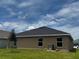 Rear exterior shows the house with its modern roof line with manicured green grass and blue skies at 3891 Sagefield Dr, Harmony, FL 34773