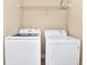 Functional laundry area featuring a side-by-side washer and dryer, along with a shelf to organize laundry essentials at 4123 Oaktree Dr, Davenport, FL 33837
