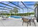 Screened-in pool area with a kidney-shaped pool, a table with umbrella, and outdoor seating for leisure and relaxation at 4123 Oaktree Dr, Davenport, FL 33837