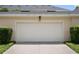 Single-car garage featuring a white door, manicured shrubbery, and a paved driveway at 4709 Fox St, Orlando, FL 32814