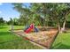 Colorful playground equipment surrounded by mature trees on a well-maintained lawn at 544 Lake Sumner Dr, Groveland, FL 34736