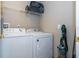 Functional laundry room equipped with a washer, dryer, storage shelf, and essential cleaning tools at 8102 Pomo Dr, Kissimmee, FL 34747