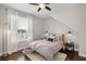 Cozy bedroom features a ceiling fan, plush bedding, and a large window with natural light at 8122 Westminster Abbey Blvd, Orlando, FL 32835