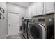 Laundry room featuring stainless steel washer and dryer, white cabinets, and a light gray tile floor at 8122 Westminster Abbey Blvd, Orlando, FL 32835