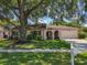 Well-maintained single-story home with mature trees and a green lawn at 8346 Mattituck Cir, Orlando, FL 32829
