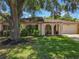 Charming single-story home with stucco exterior, arched entryway, mature tree, and well-manicured lawn at 8346 Mattituck Cir, Orlando, FL 32829