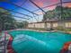 Backyard pool featuring screen enclosure, brick accents, and serene landscaping at 8346 Mattituck Cir, Orlando, FL 32829