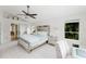 Spacious bedroom with a ceiling fan, mirrored headboard, and view of an ensuite bathroom at 9285 Wickham Way, Orlando, FL 32836