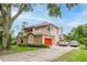 Charming two-story home with a well-manicured lawn, mature trees, and a vibrant red garage door at 9285 Wickham Way, Orlando, FL 32836