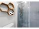 Bright bathroom featuring tiled walk-in shower, gray tile walls, and open honeycomb shelving at 1112 Spruce Ridge Ct, Minneola, FL 34715