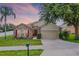 Charming single-Gathering home with stone accents, manicured lawn, and inviting front entrance with red door at 1112 Spruce Ridge Ct, Minneola, FL 34715