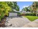 Paver driveway leading to a two-car garage, surrounded by lush landscaping at 1217 Kenwood Ave, Winter Park, FL 32789