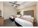 Comfortable bedroom featuring two beds with grey headboards, ceiling fan and neutral-colored walls at 12527 Floridays Resort Dr # E104, Orlando, FL 32821
