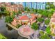Aerial view of a pool area surrounded by lush landscaping, featuring a unique building with a red tile roof at 12527 Floridays Resort Dr # E104, Orlando, FL 32821