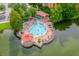 Aerial view of the waterfront pool and sunbathing deck surrounded by trees and tropical foliage at 12527 Floridays Resort Dr # E104, Orlando, FL 32821