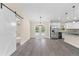 Spacious living area with gray flooring, sliding barn door, stainless steel refrigerator, and white cabinets at 12756 Sw 80 St, Dunnellon, FL 34432