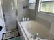 A tiled shower-tub combo with glass doors and a frosted window brings light to this bathroom at 13000 Sandy Pine Ln, Clermont, FL 34711