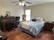 Comfortable bedroom with hardwood floors, a ceiling fan, and a large bed with decorative pillows at 13000 Sandy Pine Ln, Clermont, FL 34711