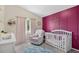 Charming Bedroom with pink accent wall, comfortable seating, and a white crib at 13691 Crystal River Dr, Orlando, FL 32828