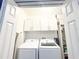Well-organized laundry room featuring front load washer/dryer, white cabinets, and storage shelves at 150 Barefoot Beach Way, Kissimmee, FL 34746