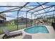 A screened-in pool is surrounded by lounge chairs and views of the neighborhood at 150 Barefoot Beach Way, Kissimmee, FL 34746