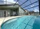 A screened-in in-ground pool featuring a secure safety fence, with outdoor dining and ample lounging space, creating an ideal backyard oasis at 150 Barefoot Beach Way, Kissimmee, FL 34746