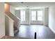 Bright living room with hardwood floors, three large windows, and staircase leading to upper level at 15119 Grove Lake Dr, Winter Garden, FL 34787