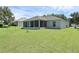 Wide view of backyard with green grass and a screened-in lanai at 189 Blackstone Creek Rd, Groveland, FL 34736