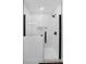 Modern walk-in shower with glass enclosure, white tile, and contemporary black fixtures at 189 Blackstone Creek Rd, Groveland, FL 34736