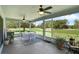 Screened-in lanai with ceiling fans, table, and view of backyard at 189 Blackstone Creek Rd, Groveland, FL 34736