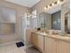 Bright bathroom featuring double sinks, a glass-enclosed shower, and tile flooring at 2222 Wyndham Palms Way, Kissimmee, FL 34747